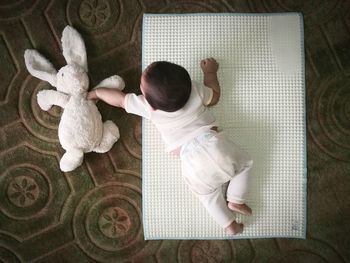 Directly above shot of baby boy playing with stuffed toy while lying on mat