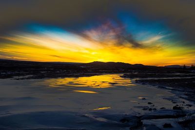 Scenic view of sea against dramatic sky during sunset