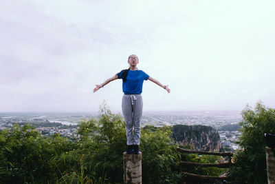 Full length of young woman standing against sky