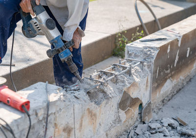 Worker using electric hammer drill to cut the wall concrete brick, close up