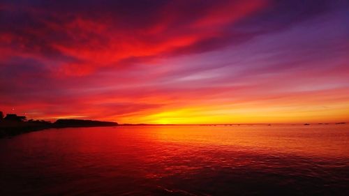 Scenic view of sea against dramatic sky during sunset