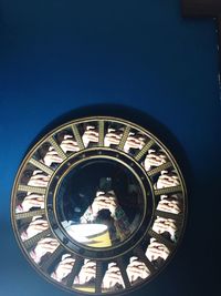 Reflection of person photographing on mirrors mounted on blue wall