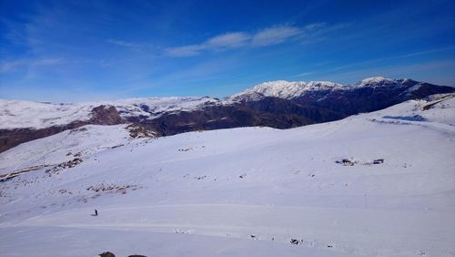 Scenic view of snow covered mountains against blue sky