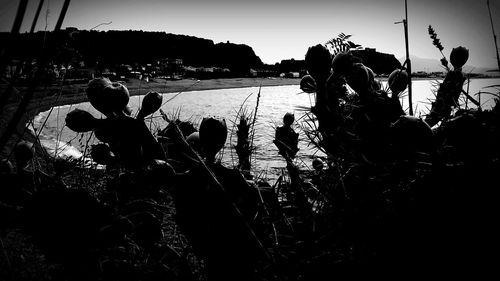 Silhouette people on beach against clear sky