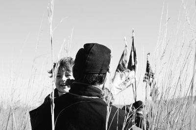 Father with son walking amidst plants on field