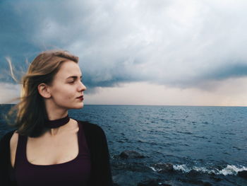 Beautiful young woman on beach against sky