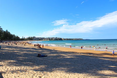 People on beach against blue sky