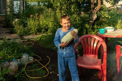 Full length of boy standing against plants in yard