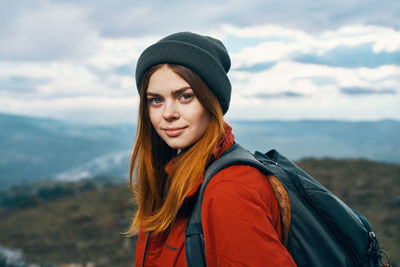 Portrait of beautiful young woman standing against sky