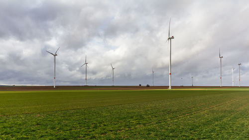 Wind turbines on field against sky