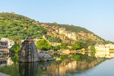 Buildings by river in town against clear sky