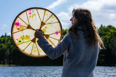 Midsection of woman holding umbrella against sky