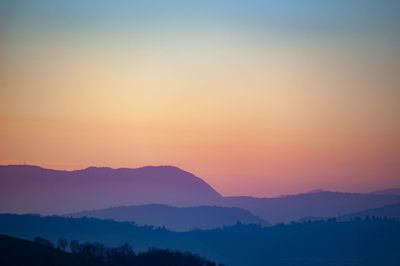 Scenic view of silhouette mountains against orange sky