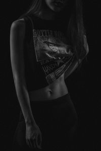 Midsection of woman standing against black background