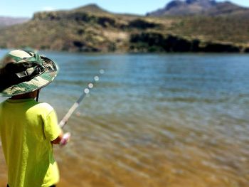 Boy holding leaf in water against sky