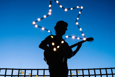 Low angle view of silhouette man against illuminated clear sky