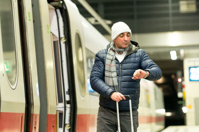 Man checking time while standing at railroad station platform