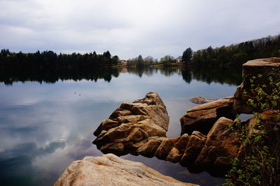 Rocks by lake against sky