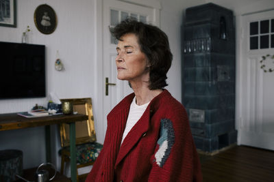 Senior woman with eyes closed meditating at home