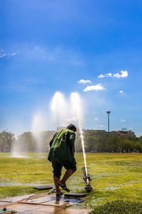 Man climbing on golf course against sky