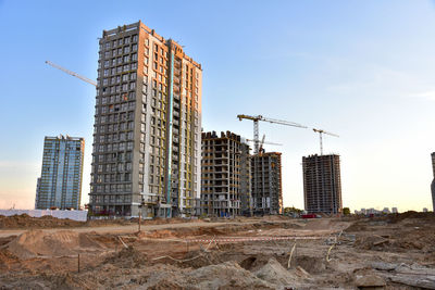 View on the large construction site with tower cranes and buildings on sunset background.