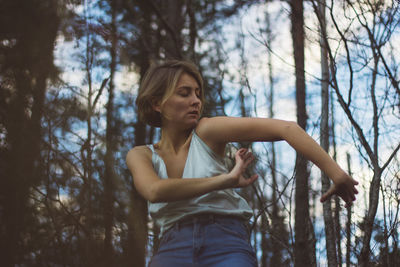 Low angle view of young woman dancing in forest