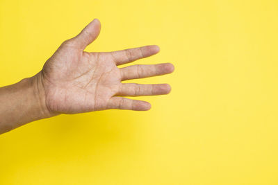 Close-up of human hand against yellow background