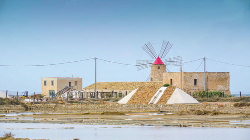 Traditional windmill by building against clear sky