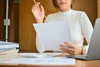 Midsection of businesswoman using laptop on table