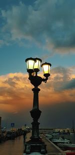 Low angle view of illuminated street light against sky at sunset