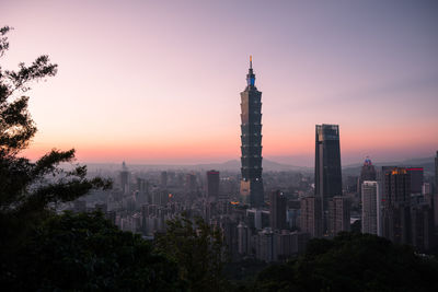Modern buildings in city against sky during sunset