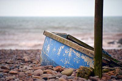 Close-up of abandoned boat on beach against sky