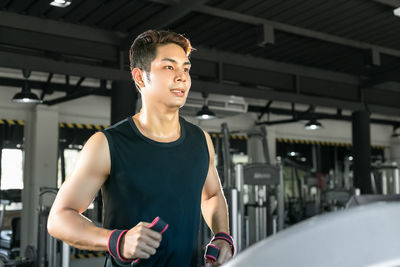 Young man exercising on treadmill in gym