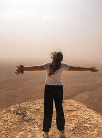 Rear view of woman standing on viewpoint in desert.  view of empty desert landscape. 