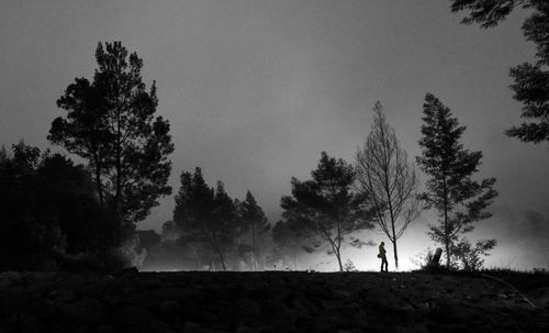 Silhouette trees on field against sky