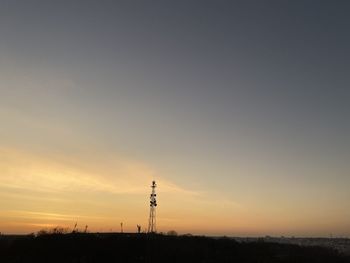 Silhouette tower on field against sky during sunset