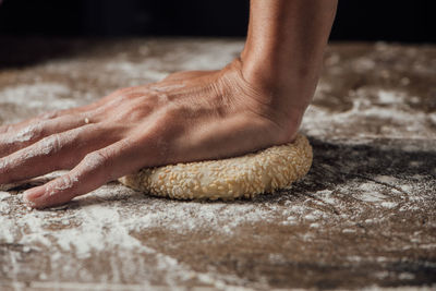 Cropped hand kneading dough on table