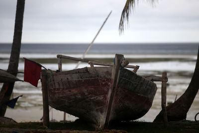 Close-up of damaged boat moored at beach