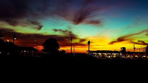 Silhouette of city against dramatic sky at sunset