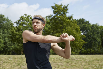 Young man with arms outstretched standing against plants