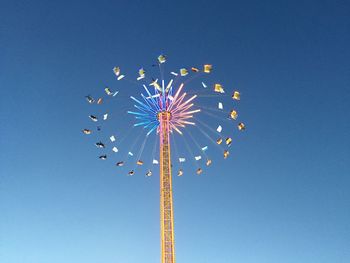 Low angle view of ferris wheel against clear blue sky