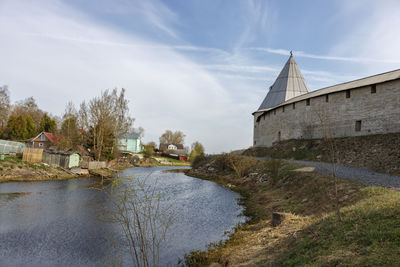 Buildings by river against sky