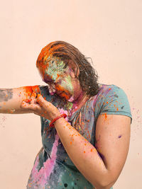 Portrait of happy indian woman celebrating holi with powder colours or gulal. indian festival holi.