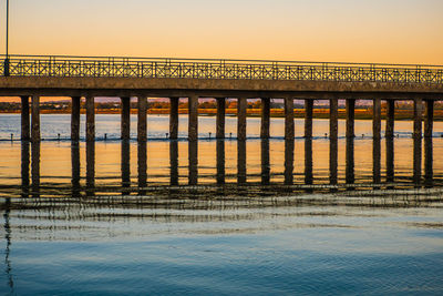 Bridge over sea against clear sky during sunset