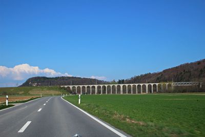 Road by landscape against clear blue sky