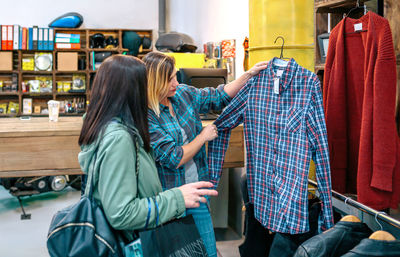 Female client looking plaid shirt while receives personalized support from friendly shop assistant