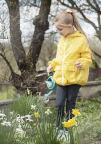 Little girl in a garden with green watering pot