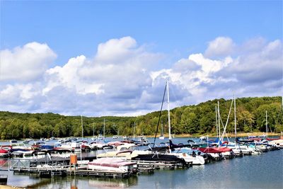 Boats moored at harbor against sky