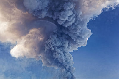 Low angle view of smoke emitting from blue sky