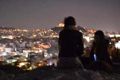 Rear view of people in city against sky at night